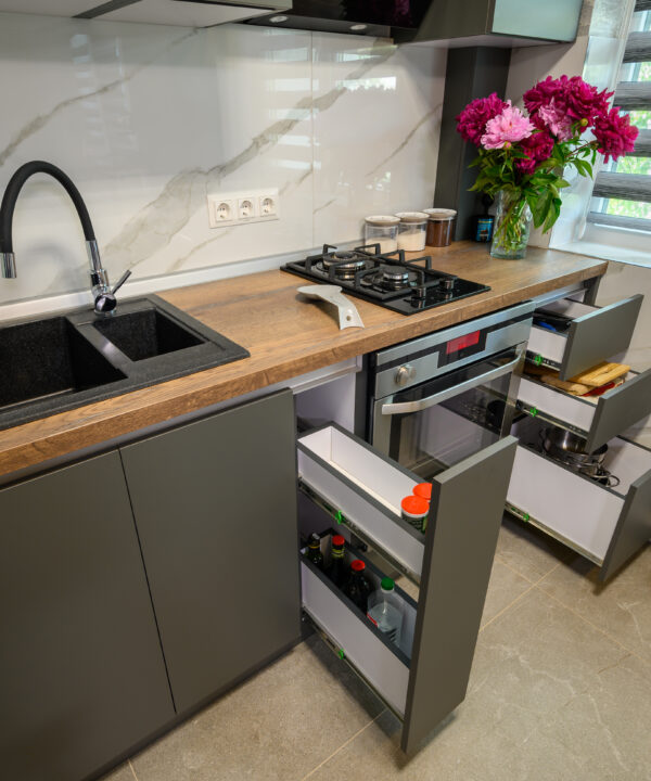 Real showcase interior of small modern trendy gray kitchen, drawrs retracted to show inside, high angle view