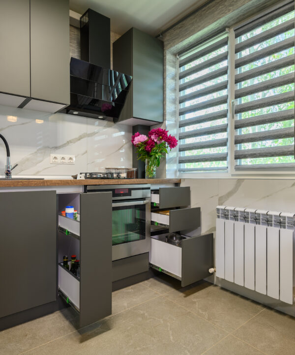 Real showcase interior of small modern trendy gray kitchen, drawrs retracted to show inside