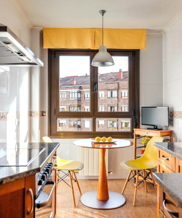 Interior of kitchen on two fronts with dining area next to the window