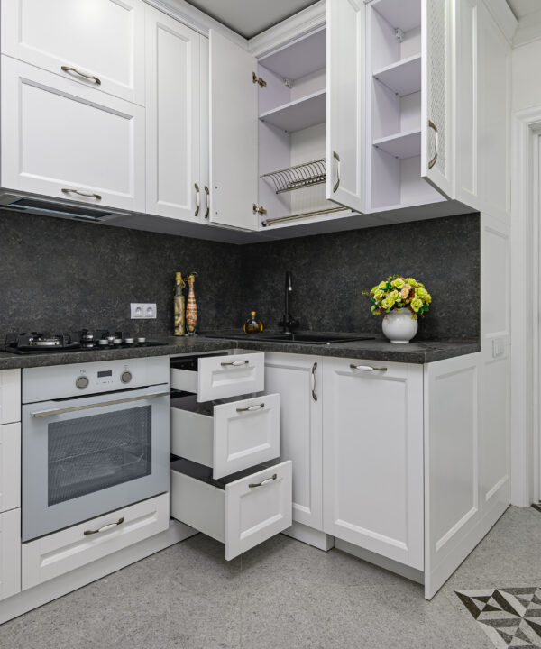 Open doors and drawers of furniture at modern black and white woden kitchen in classic style