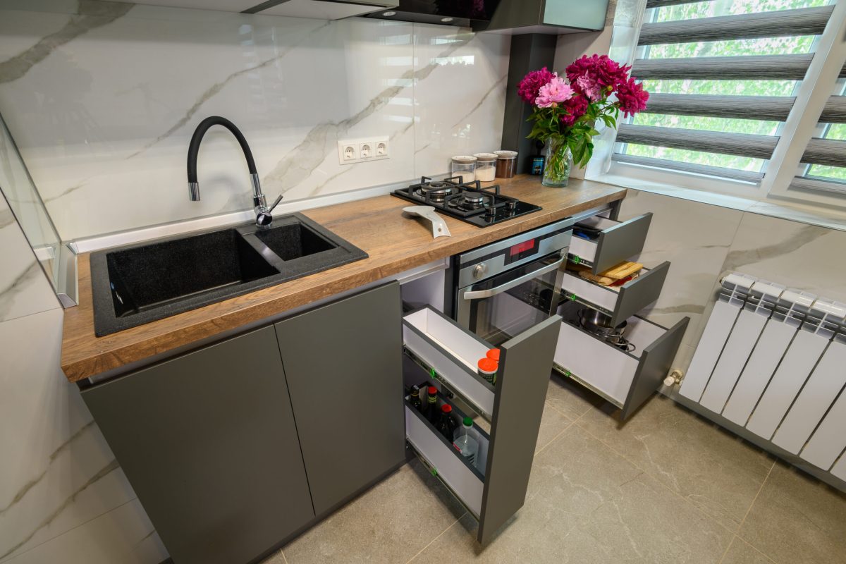 Real showcase interior of small modern trendy gray kitchen, drawrs retracted to show inside, high angle view