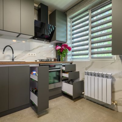 Real showcase interior of small modern trendy gray kitchen, drawrs retracted to show inside