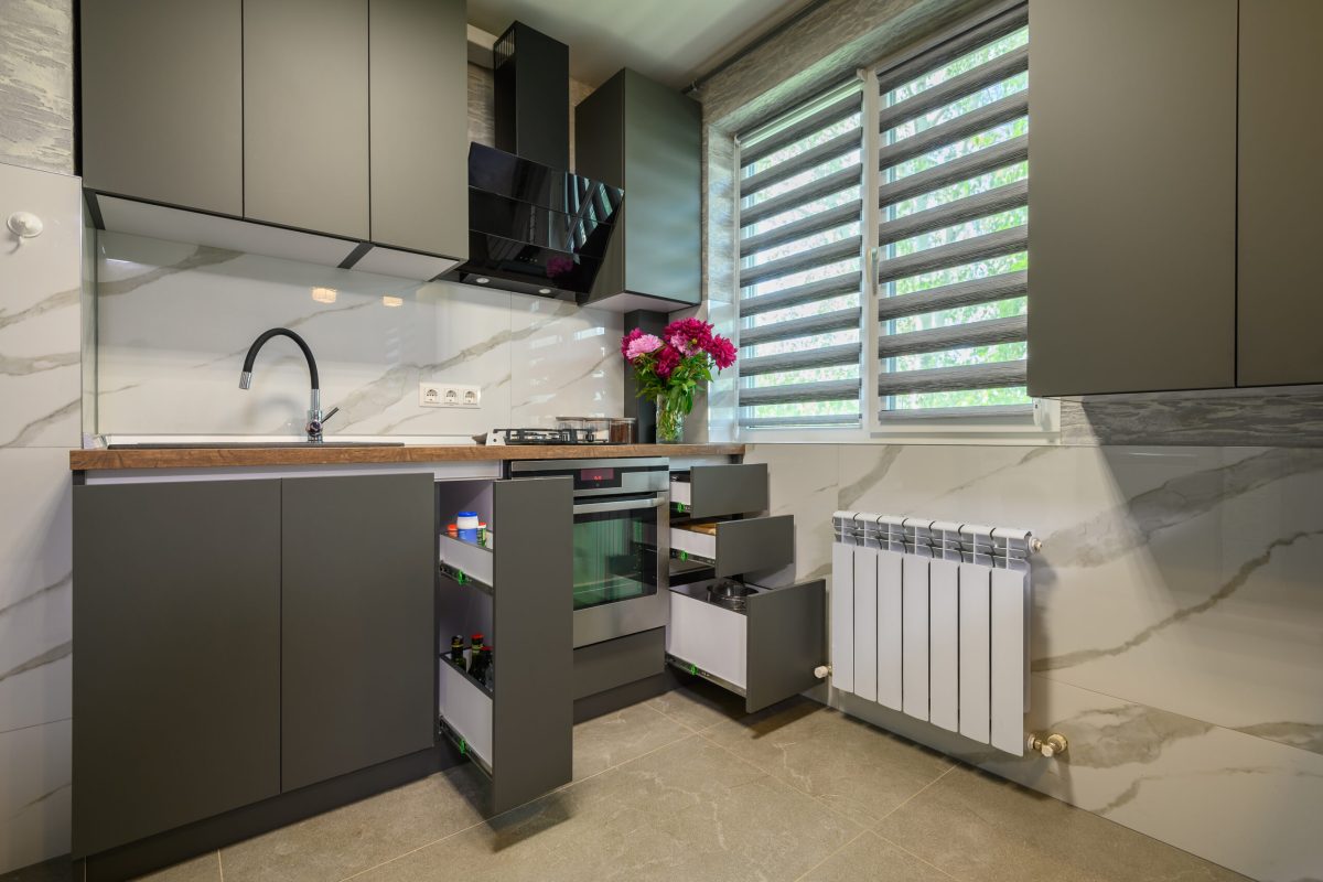 Real showcase interior of small modern trendy gray kitchen, drawrs retracted to show inside