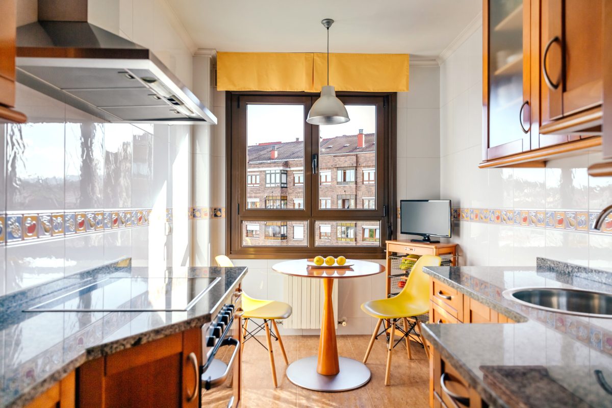 Interior of kitchen on two fronts with dining area next to the window