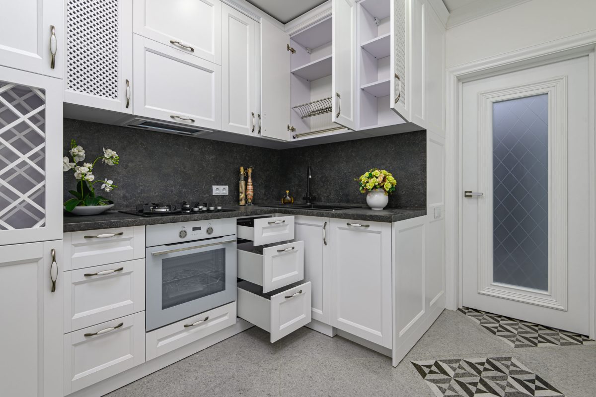 Open doors and drawers of furniture at modern black and white woden kitchen in classic style