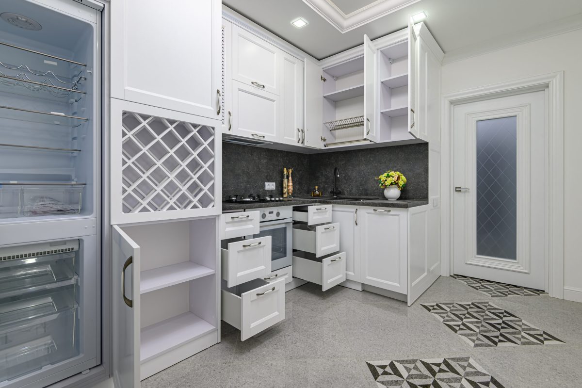 Open doors and drawers at modern black and white woden kitchen in classic style